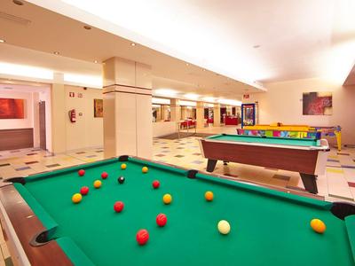 Sala giochi dell'hotel con tavoli da biliardo, palle colorate e luce brillante.
