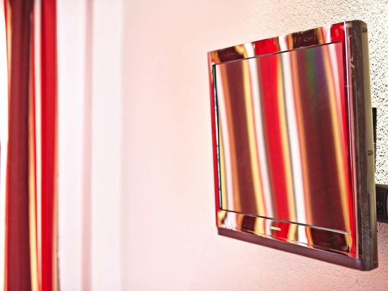 Tende a righe rosse appese vicino a una parete rosa con una cornice scura.