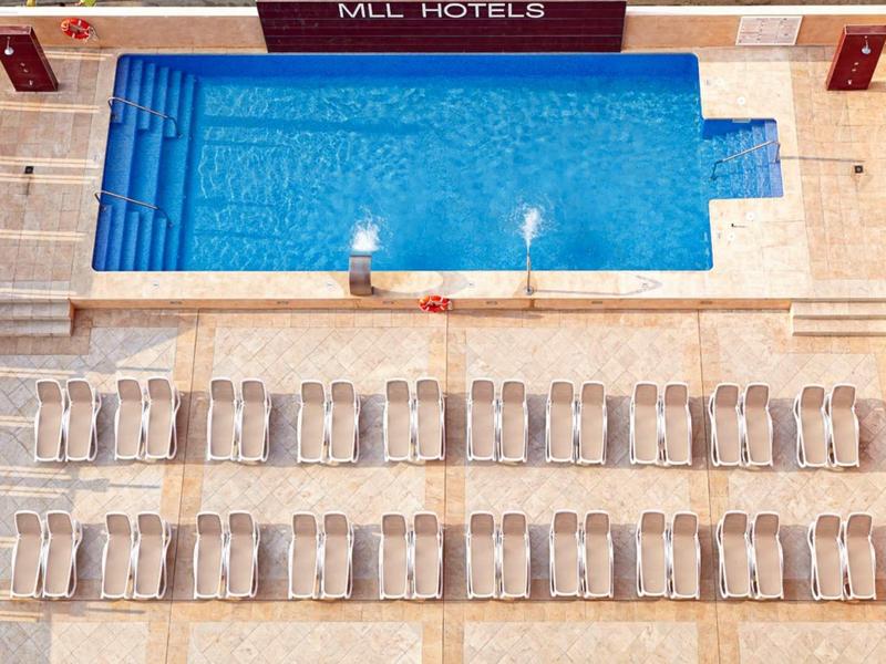 Piscina blu con lettini allineati in un moderno hotel.