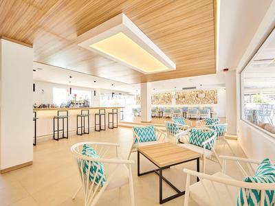 Bright, modern lounge and bar area with wooden ceilings and turquoise patterned cushions.