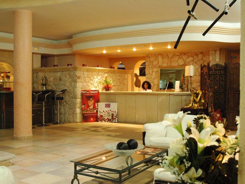 Bright hotel lobby area with cozy seating, flower table, and bar counter in the background.