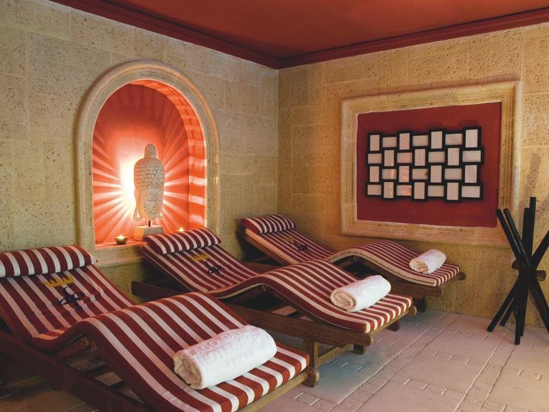 Relaxation room with three loungers featuring red and white stripes and white towels.