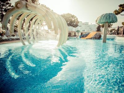 Piscina infantil con toboganes de agua y sol al aire libre en un resort vacacional