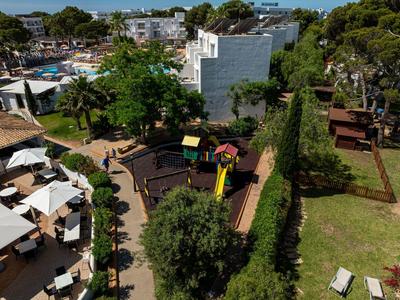 Vista de un parque infantil de hotel con toboganes y áreas de descanso en un entorno verde.