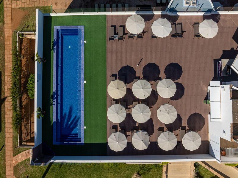 Terraza en la azotea con piscina, sombrillas y áreas de asientos en un hotel.
