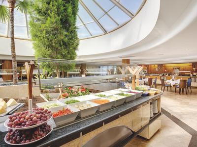 Buffet mit frischem Obst, Gemüse und Salaten in einem modernen, hellen Restaurant.