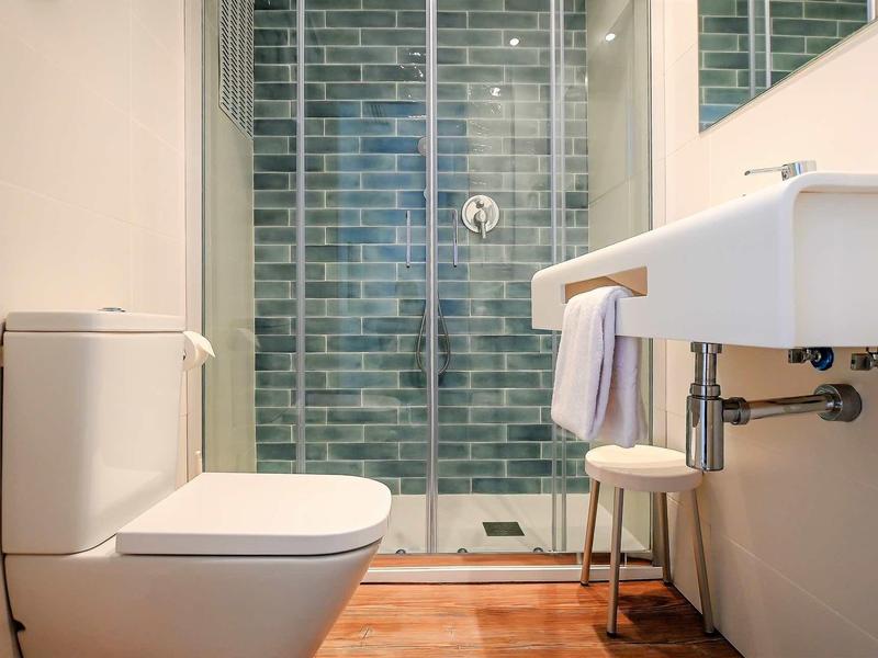 Modern bathroom with toilet, sink, and glass door shower.