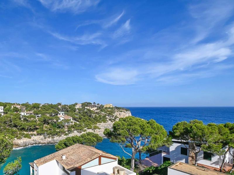 View of a coastal landscape with blue sea, green trees, and white houses.