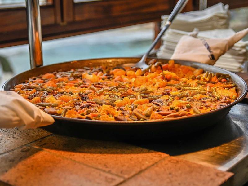 Large pan filled with colorful rice dish with vegetables and meat.