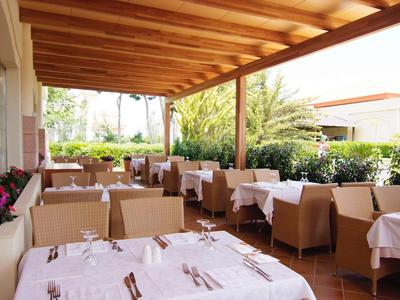 Überdachte Terrasse mit weißen Tischdecken, braunen Stühlen und Holzdach in hellem Ambiente.