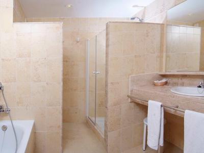 Modernes Badezimmer mit Badewanne, Glasdusche und Waschbecken in hellen Beige- und Cremetönen.