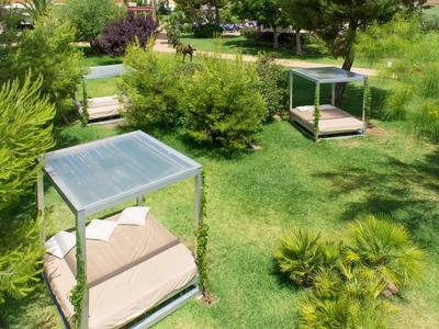 Grüne Parkanlage mit Gras, Büschen und vier modernen, quadratischen Sitzliegen mit Sonnenschutz.