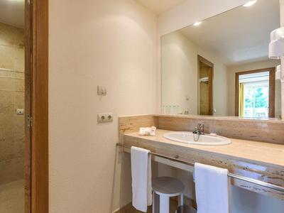 Helles Badezimmer mit großem Spiegel, Waschbecken, Handtüchern und separater Toilette.