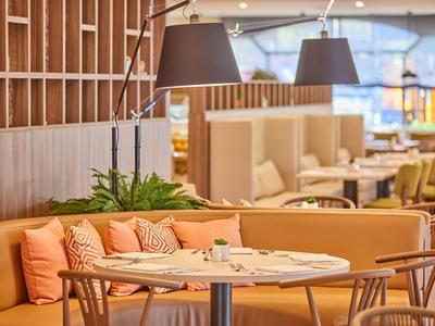 Moderne hotel lobby met comfortabele banken, ronde tafels en warme verlichting.