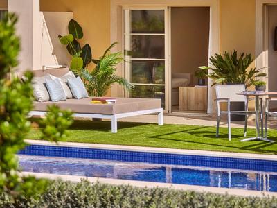 Moderne patio met ligstoel, stoelen en groen gazon naast een blauw zwembad.