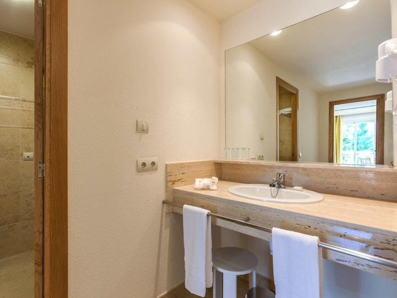 Helles Badezimmer mit großem Spiegel, Waschbecken, Handtüchern und separater Toilette.