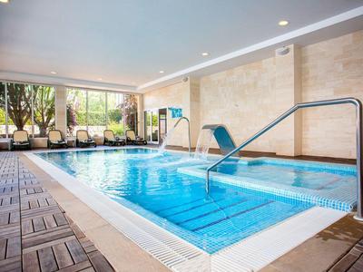 Innenpool mit blauen Wasser und Sitzbereich neben großen Fenstern.