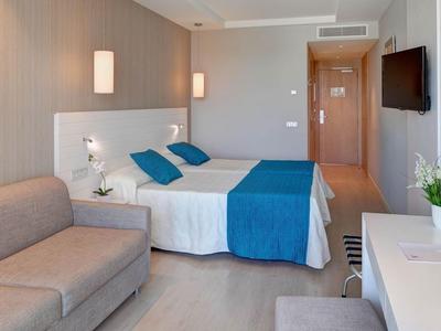 Camera d'hotel moderna con letto matrimoniale, divano, scrivania e TV.