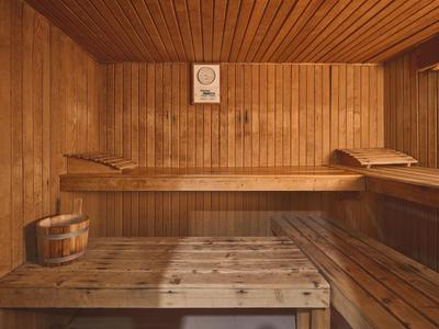 Interno di una sauna con panche di legno, pareti in legno e un secchio di legno.