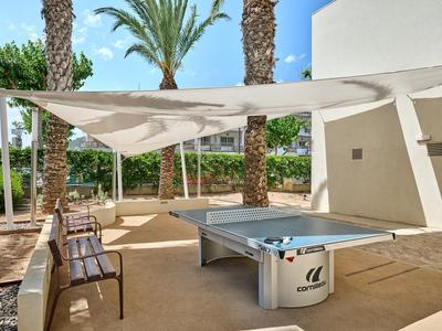 Area moderna per ping pong sotto tende bianche in un hotel con palme.