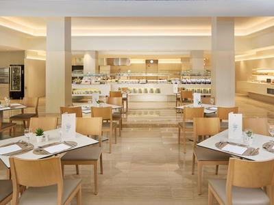 Sala colazione moderna con mobili in legno chiaro e area buffet.