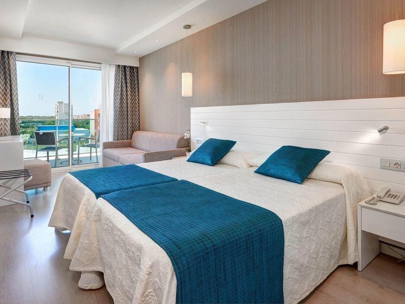 Modernes Hotelzimmer mit Doppelbett, Schreibtisch und Balkon mit Meerblick.