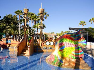 Bunter Wasserspielplatz mit Palmen und blauen Wasserflächen in einem Ferienresort.