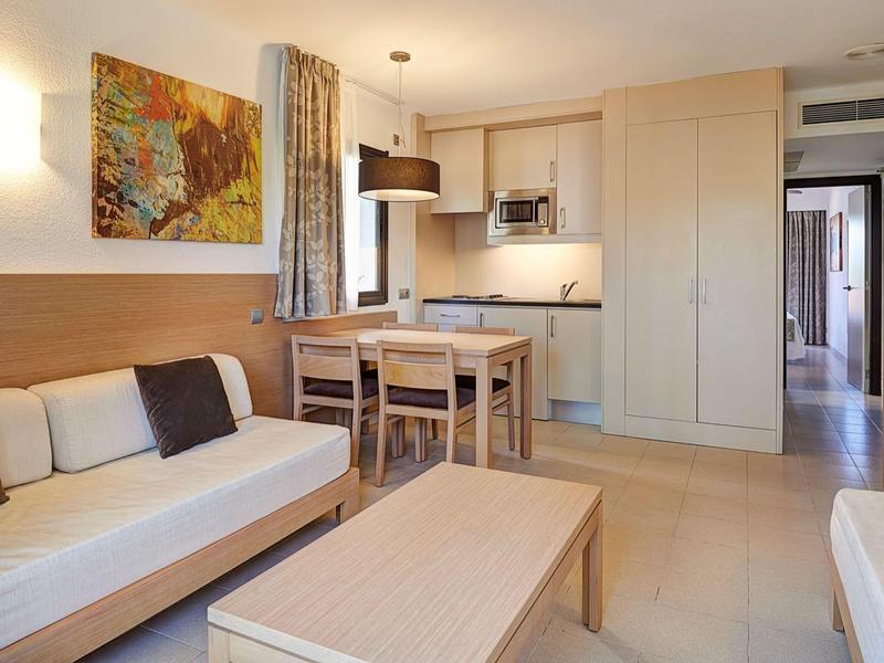 Modern eingerichtetes Apartment mit Küchenzeile, Esstisch und Sofa.