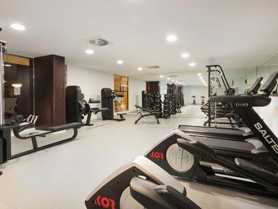 Palestra moderna con tapis roulant, macchine per il sollevamento pesi e pareti chiare in un hotel.