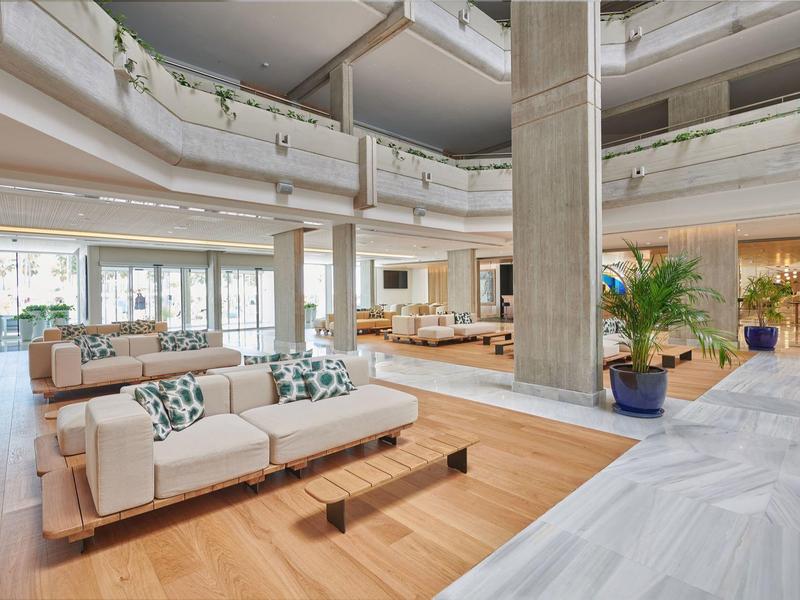 Przestronny, nowoczesny hol hotelowy z beżowymi kanapami i naturalnym światłem.