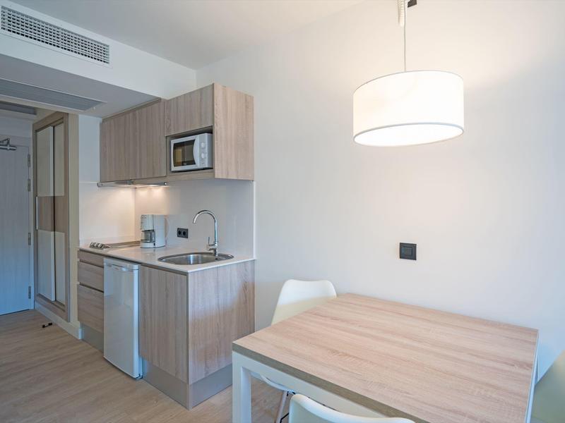 Small modern kitchenette with table and chairs in a hotel room.