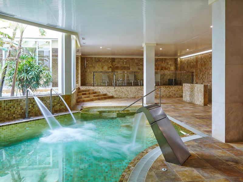 Indoor area with heated pool, water features, and marble finishes in the spa area.