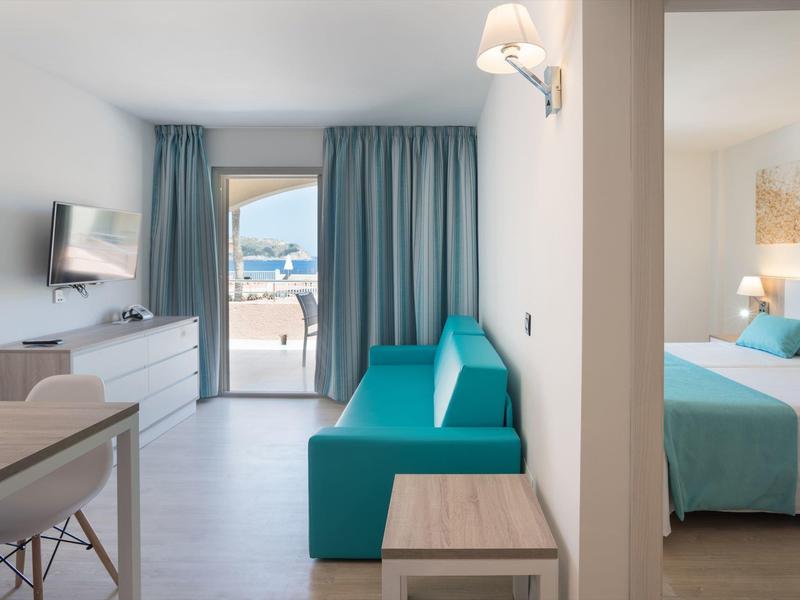 Modern hotel room with living area, terrace, and adjoining bedroom.