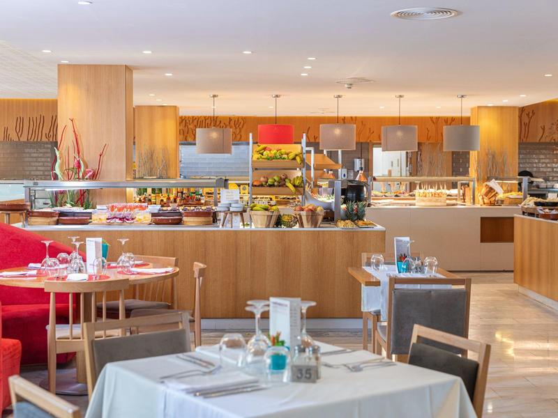 Ristorante luminoso con interno moderno in legno e tavoli ben apparecchiati.