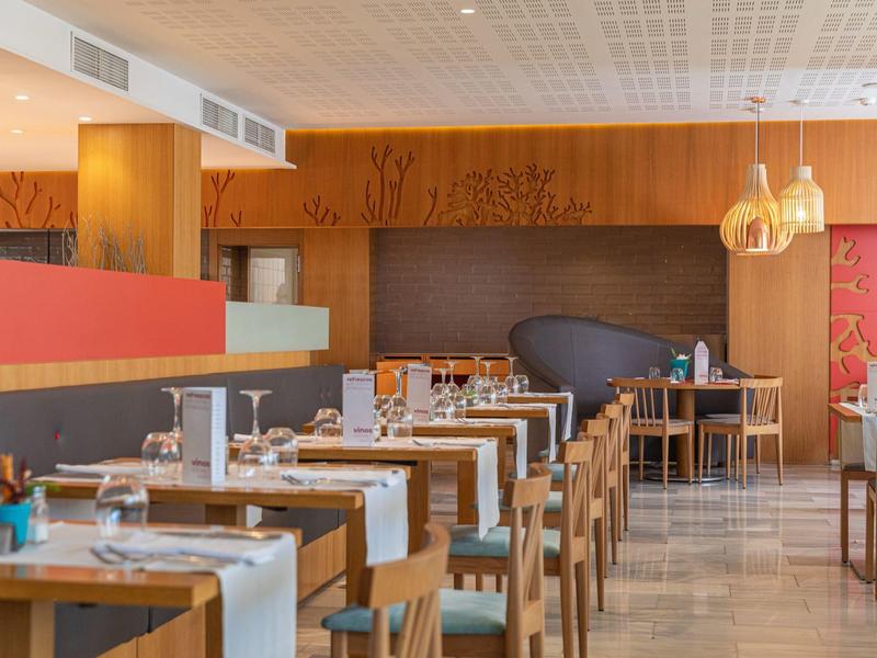 Ristorante moderno con sedie in legno e tavoli apparecchiati in un'atmosfera calda e accogliente.