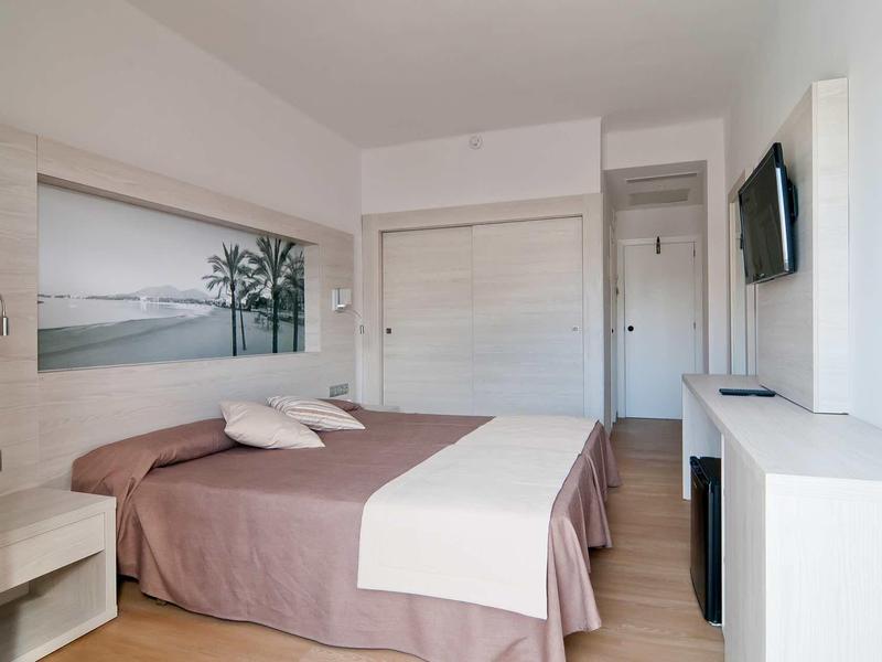 Chambre d'hôtel lumineuse avec lit double, tableau mural et télévision à écran plat.