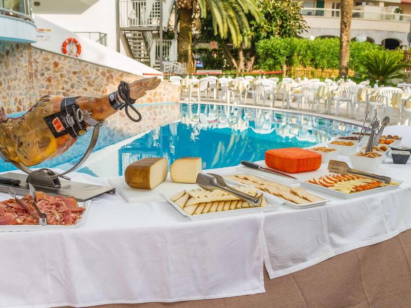 Buffet de charcuterie, fromages et pains en extérieur d'un hôtel.