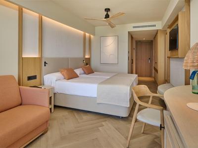 Modern ingerichte hotelkamer met tweepersoonsbed, bank en bureau.