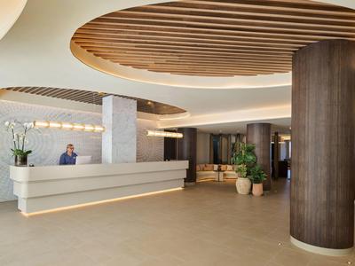 Moderne hotellobby met receptiebalie, zitgedeelte en ronde houten plafondontwerp.