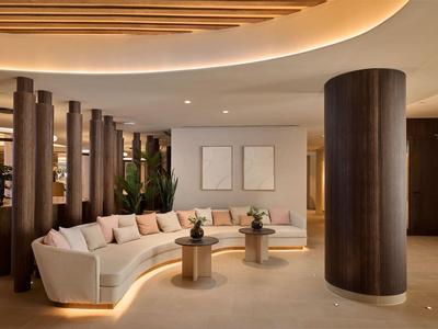 Moderne hotel lounge met gebogen bank en houten zuilen.