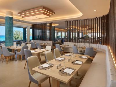 Modern, stijlvol restaurant met elegante houten tafels en comfortabele stoelen met uitzicht op zee.