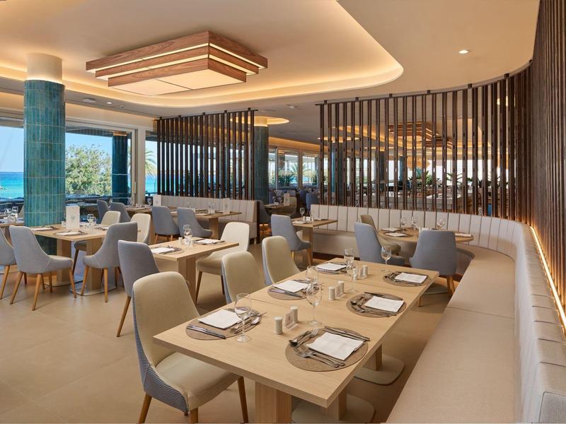 Modern, stijlvol restaurant met elegante houten tafels en comfortabele stoelen met uitzicht op zee.