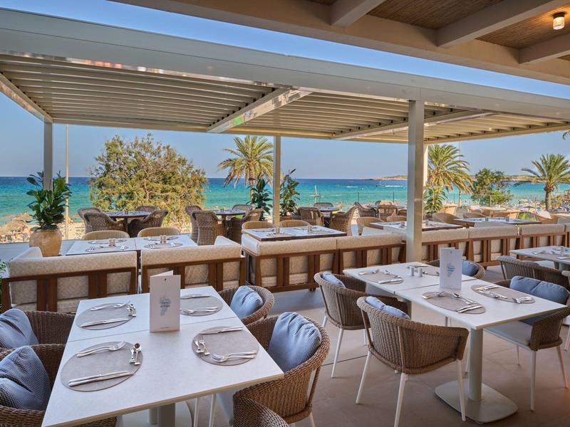 Open restaurant met zeezicht en modern, comfortabel meubilair op een zonnige dag.