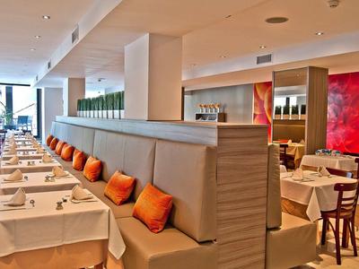 Espace de restaurant lumineux avec nappes blanches et coussins orange sur les banquettes.