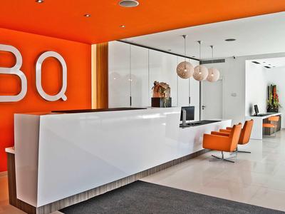 Hall d'hôtel moderne avec comptoir blanc et accents orange.