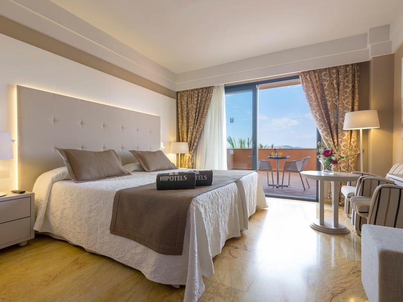 Camera d'albergo luminosa con letto matrimoniale, balcone e vista mare.