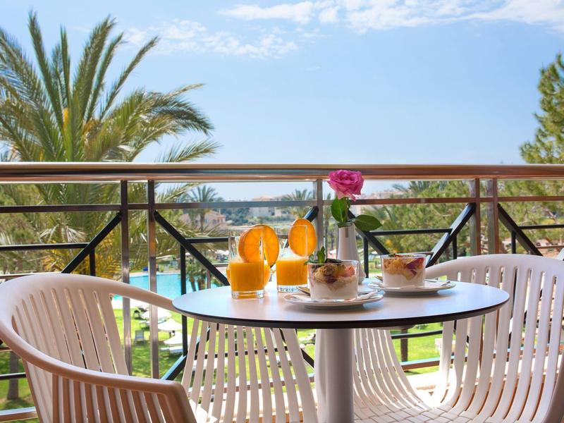 Terrazza con tavolo e sedie, vista mare, asciugamani e bevande arancioni.