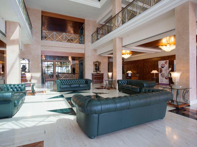 Hall dell'hotel moderno con divani in pelle e area interna su due piani.