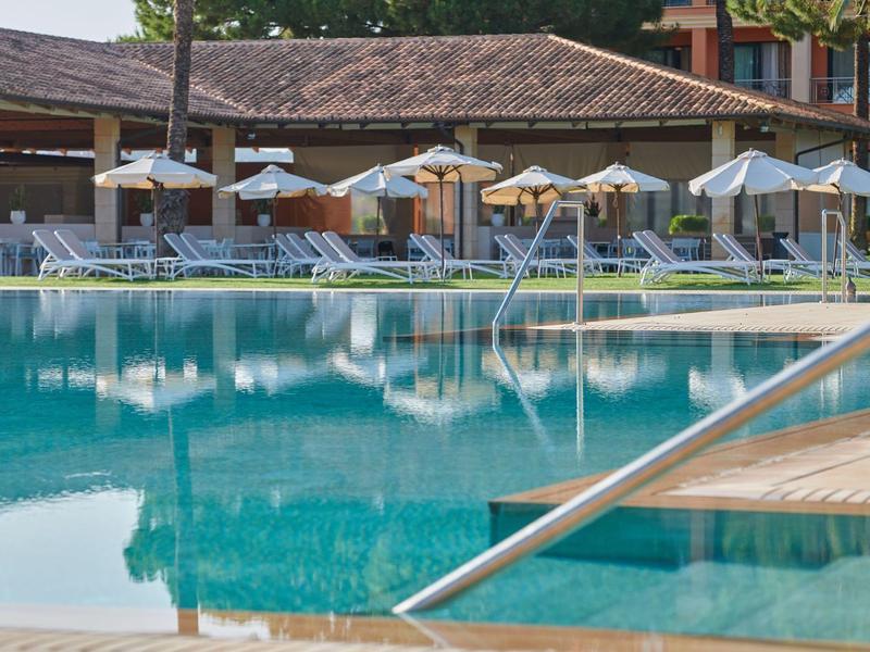 Piscina vuota con sedie a sdraio e ombrelloni in un resort hotel.
