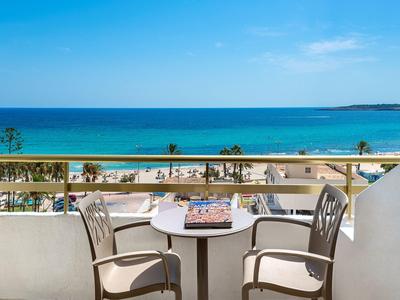 Balkon mit zwei Stühlen und Tisch mit Blick auf das Meer und den Strand bei klarem Himmel